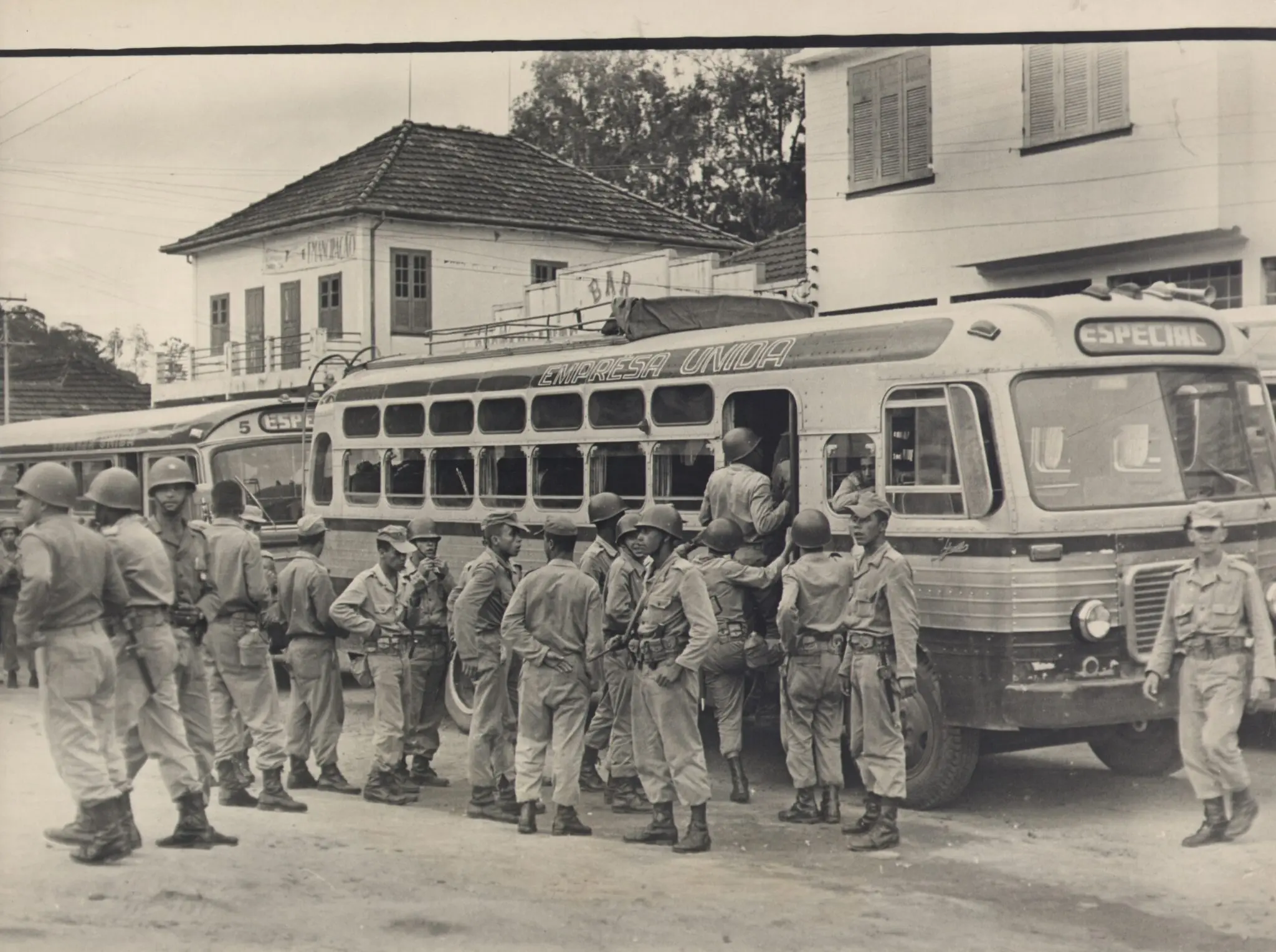 Soldados em frente a ônibus, assunto: transporte militar.