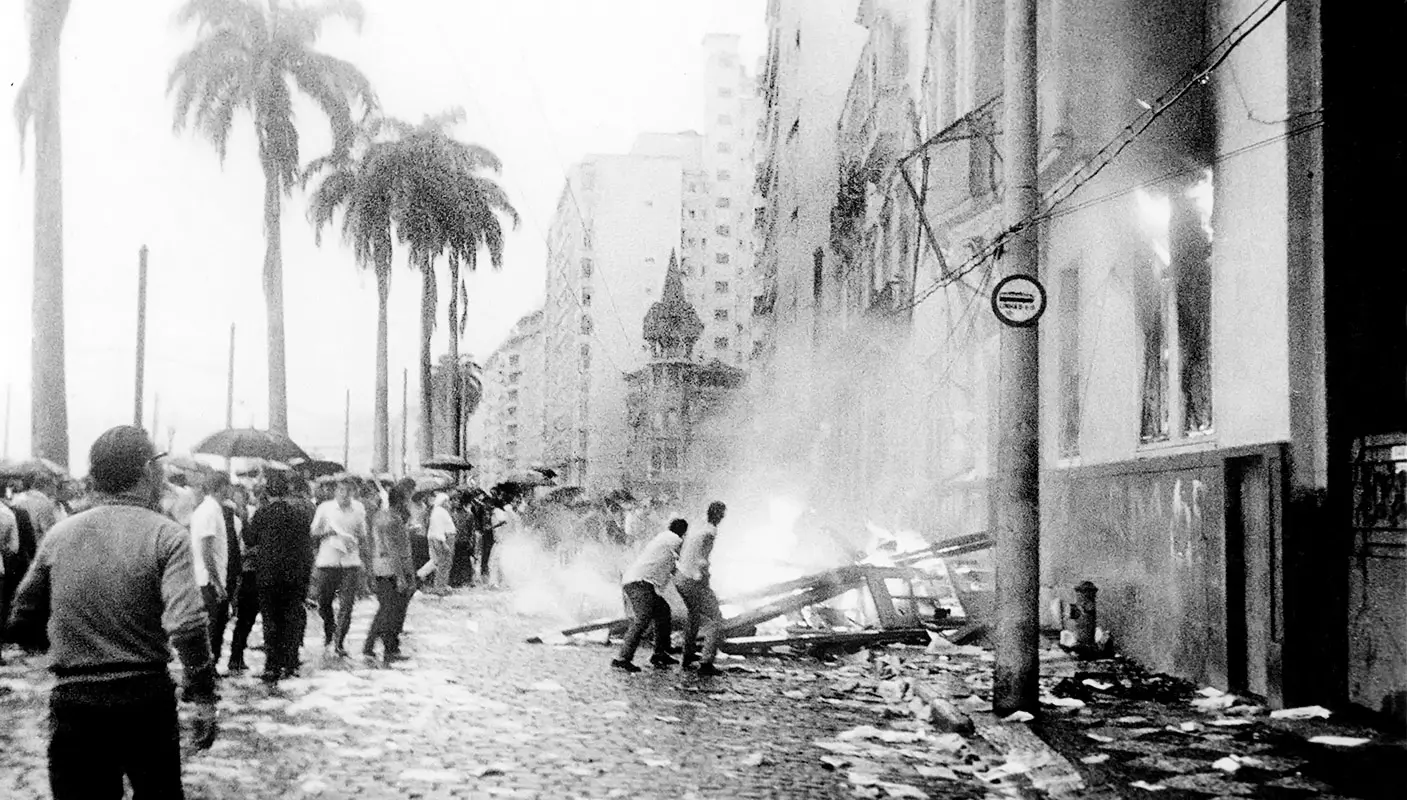 Destroços e fumaça em uma rua urbana.