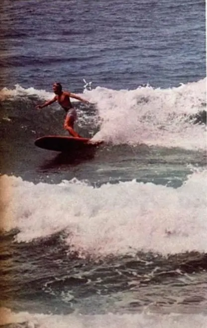 Surfista equilibrado em ação no mar, com ondas ao fundo.