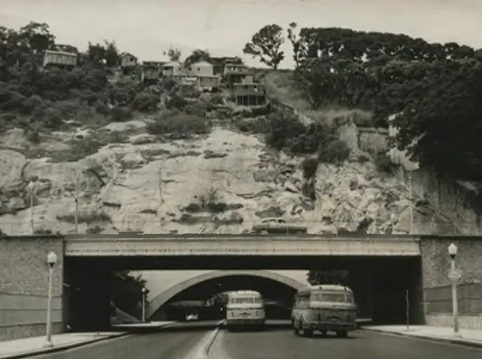 Cena urbana com túnel e casas nas encostas.