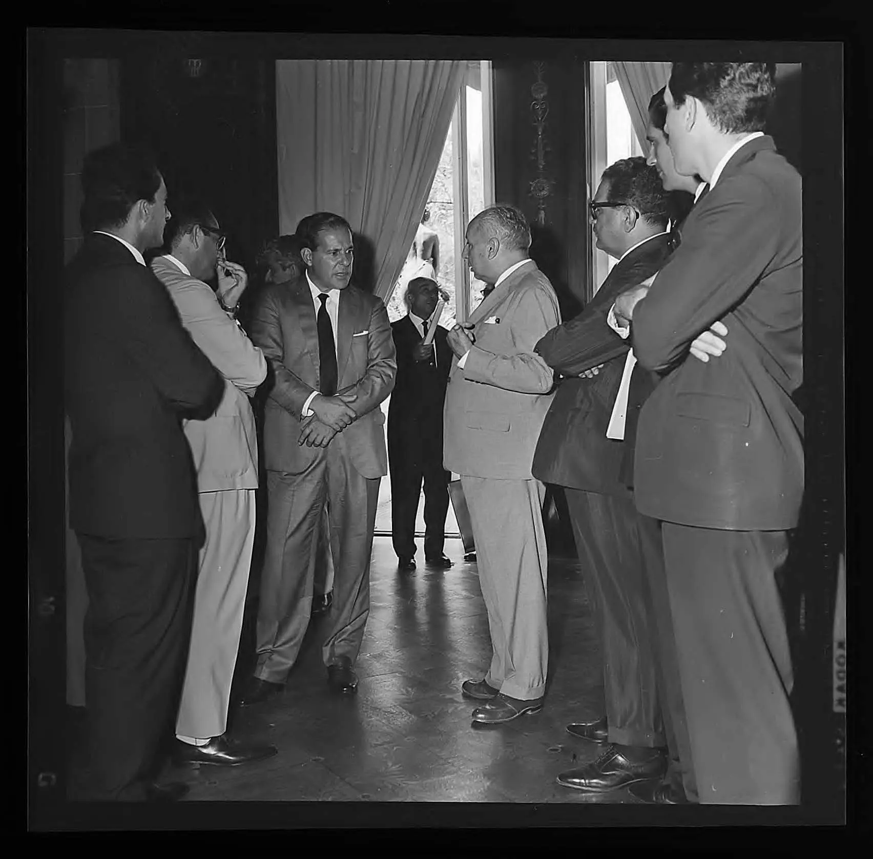Reunião de homens em ambiente interno, conversas e movimento.