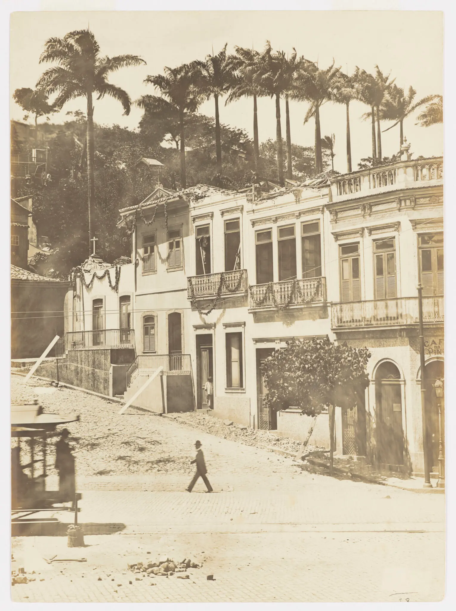 Uma rua histórica com construções antigas e palmeiras ao fundo.