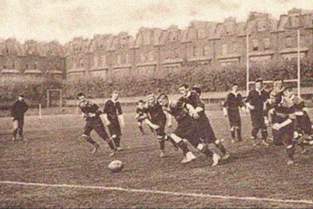 Jogadores em ação durante partida de futebol em campo urbano.