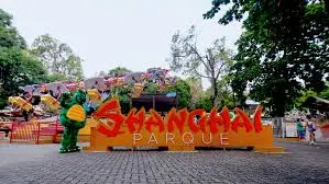 Parque com estrutura colorida, letras "Shanghai" e árvores verdes.