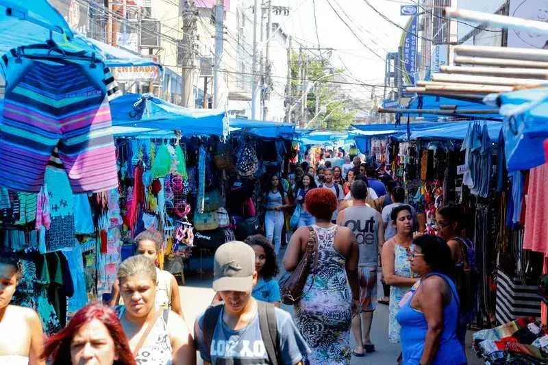 Mercado ao ar livre com barracas coloridas e pessoas caminhando.