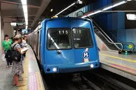 Metrô em movimento com plataforma e passageiros.