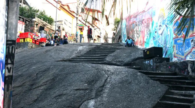 Uma rua com grafites e pessoas caminhando.