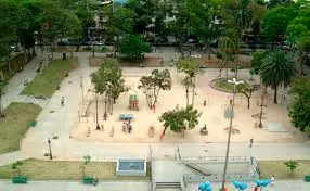 Praça com árvores, monumento, playground e escultura de animais.