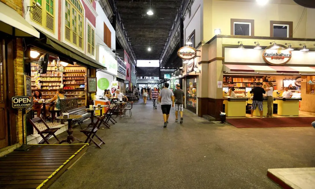 Mercado interno com lojas e pessoas caminhando.