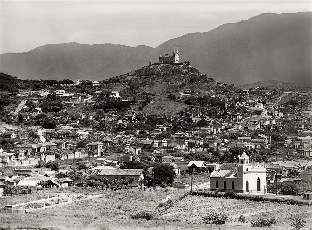 Cidade com basílica em monte, casas espalhadas pela planície.