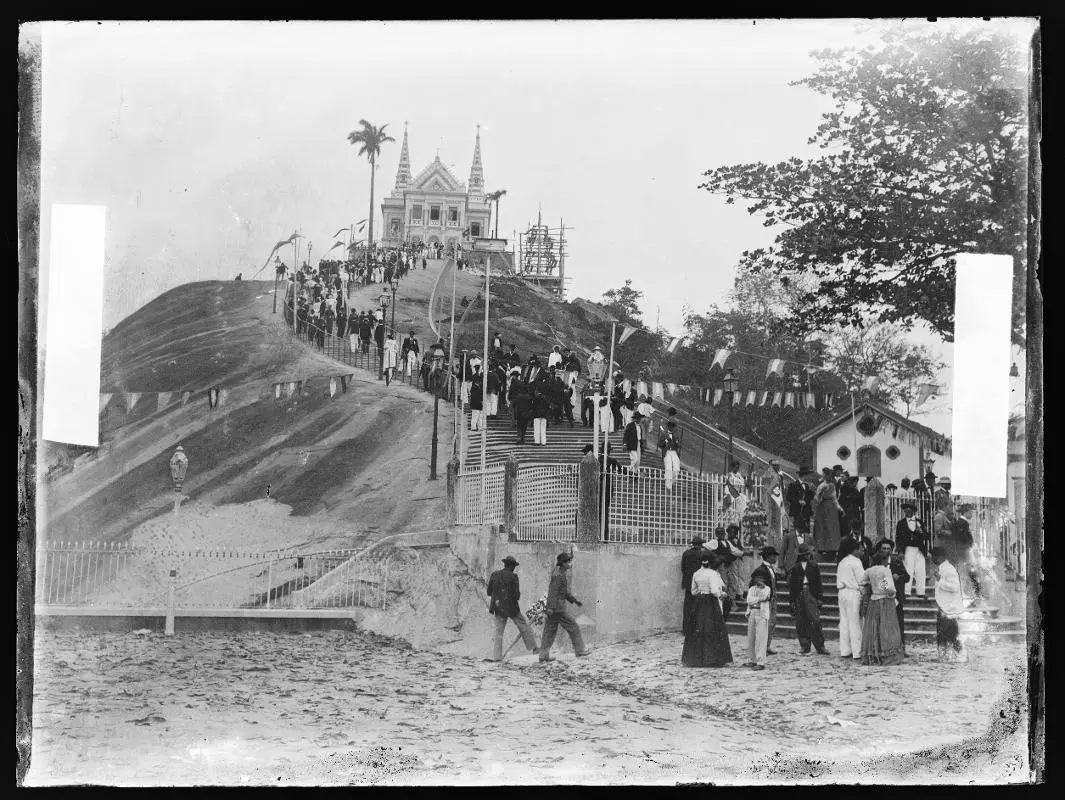 Escadaria antiga com pessoas caminhando em direção a um edifício religioso.