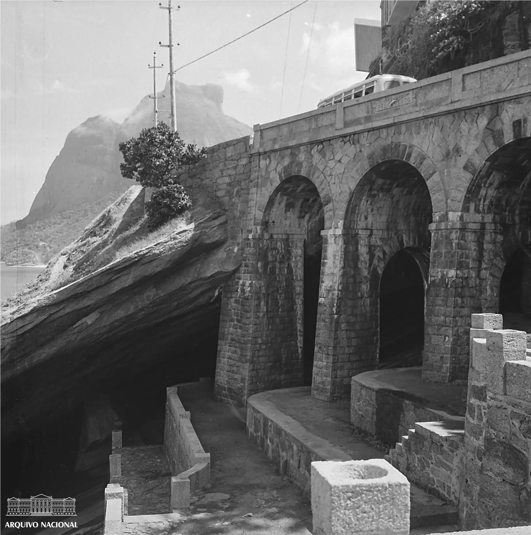 Mirante preto e branco com rocha, arcos de pedra e teleférico em Leblon, RJ.