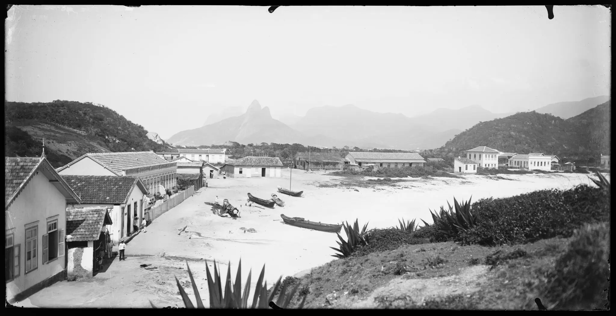 Colônia de pescadores em praia histórica, preto e branco.