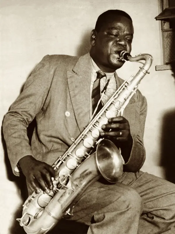 Músico toca saxofone em preto e branco.