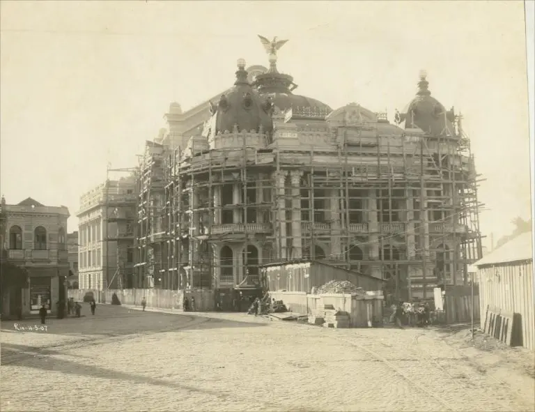 Teatro em construção com estrutura metálica e cúpulas ornamentadas.
