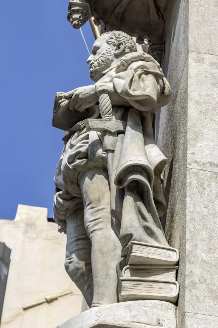 Estátua de pedra antiga em frente a edifício clássico.