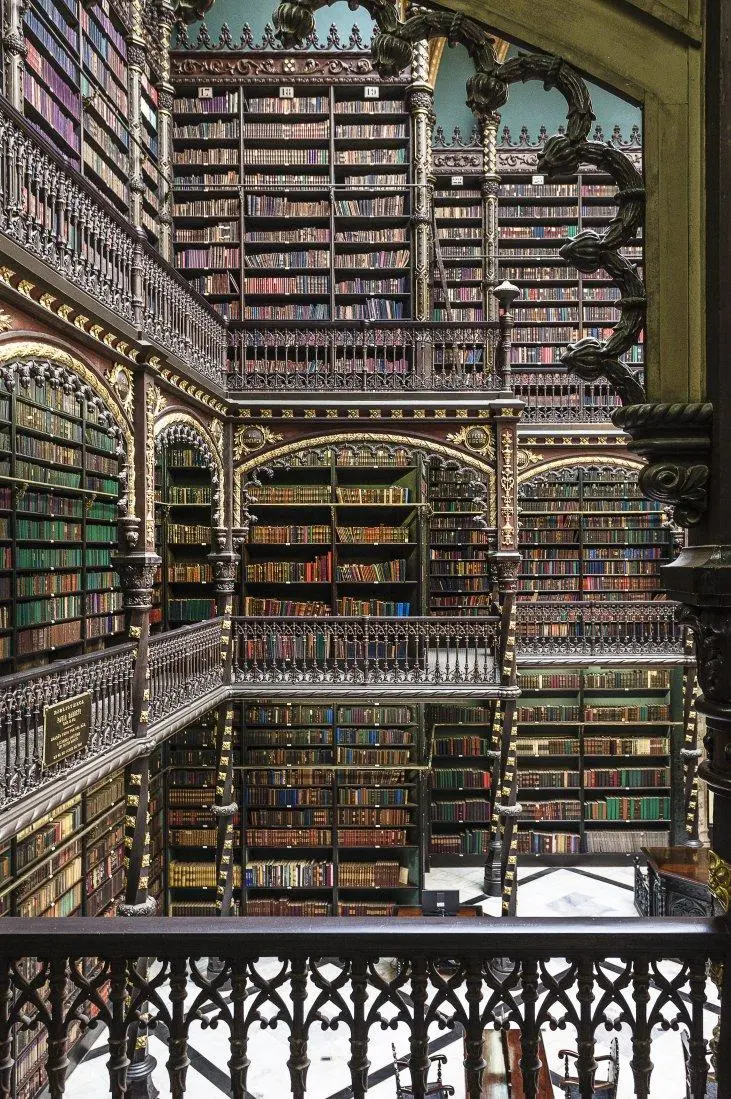 Biblioteca histórica com prateleiras coloridas e ornamentos dourados.