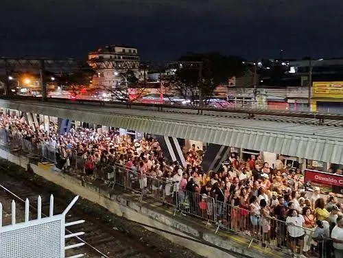 Multidão aglomerada em estação de metrô, com edifício "Oswaldo Cruz" à direita.
