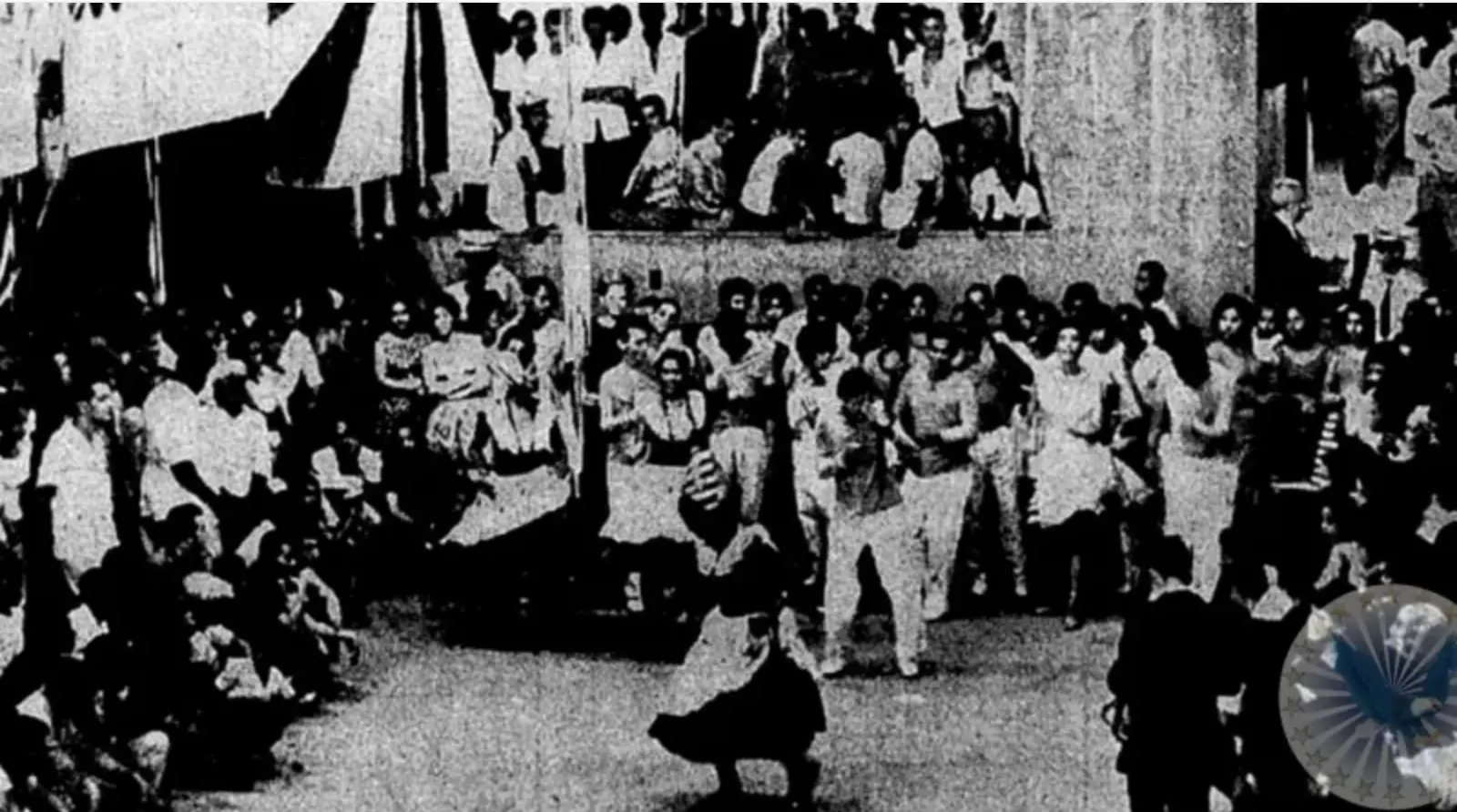 Multidão em evento tradicional, dança e bancos elevados.