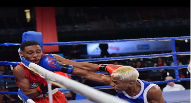 Combate de boxe em ringue com lutador vermelho sendo socado por lutador azul.