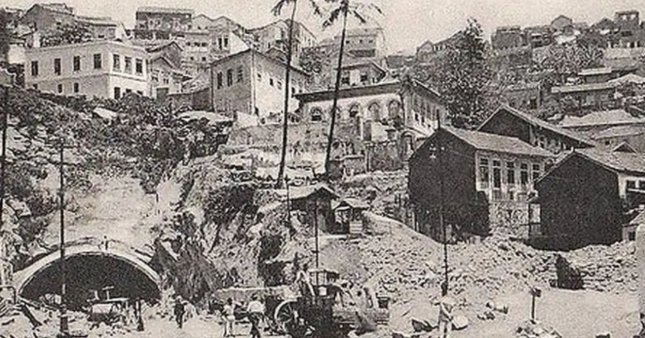 Imagem urbana danificada com túnel, destroços, edifícios e cidade densa.
