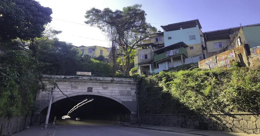 Túnel urbano com estrutura de pedra e casas coloridas ao fundo.