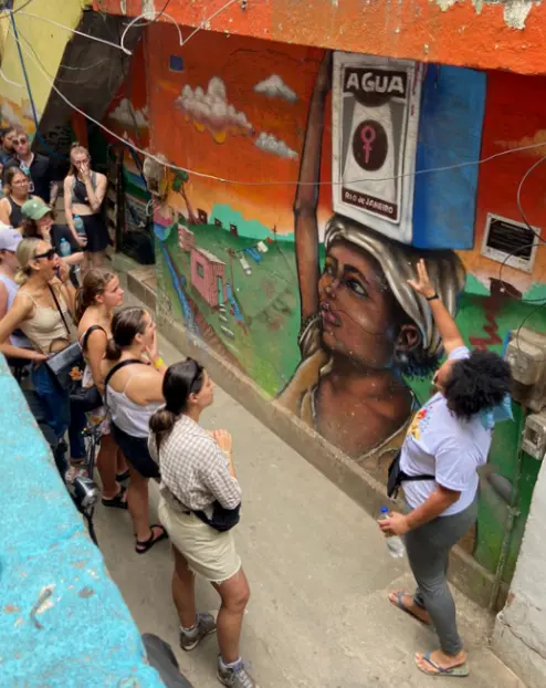 Grupo observando mural colorido em favela.