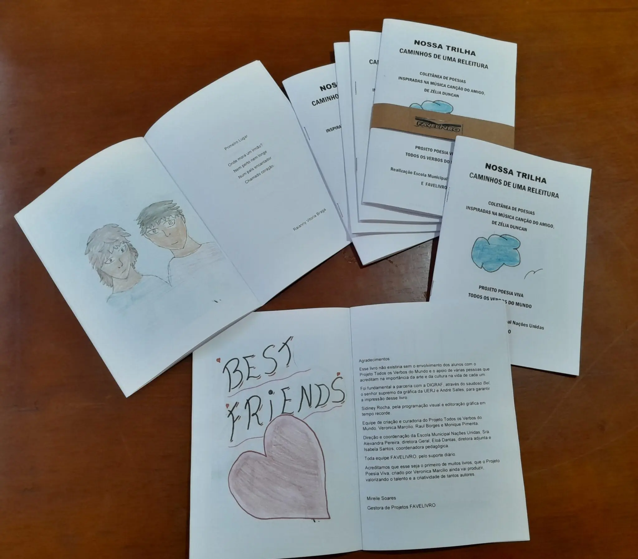Folhetos sobre madeira, "Best Friends" e "Nossa Trilha Caminhos de Uma Releitura".