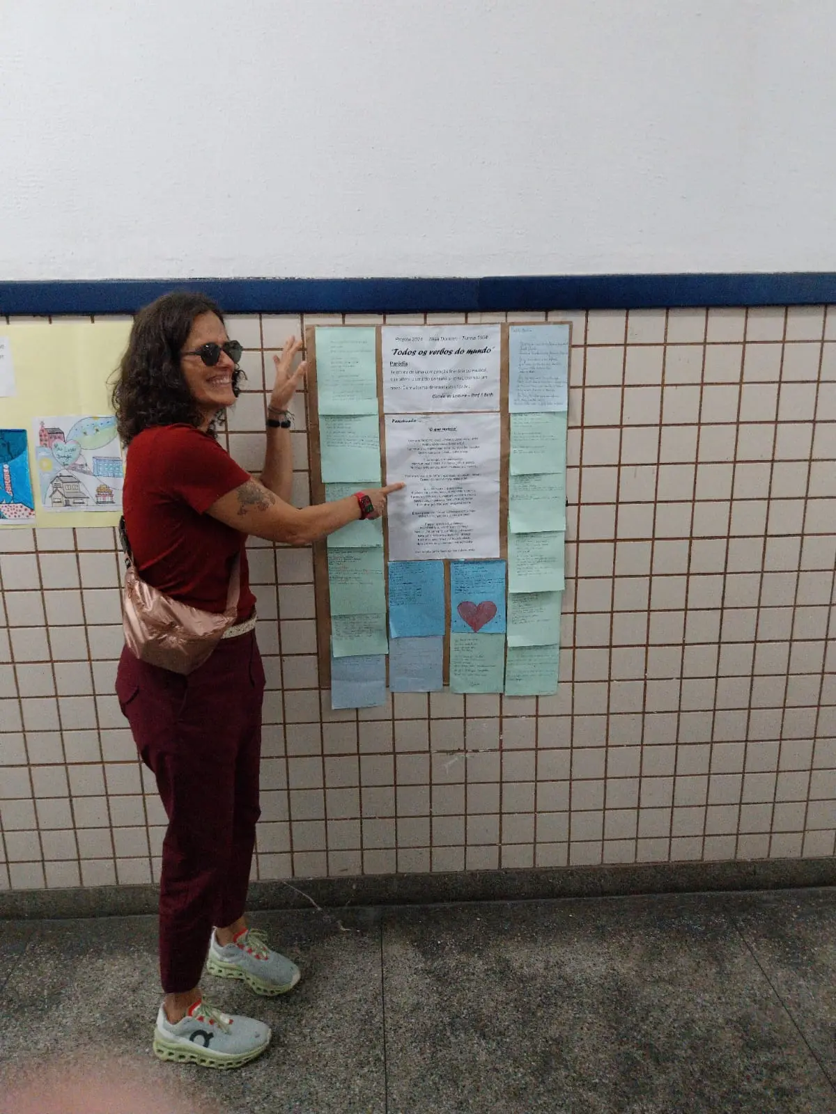 Pessoa interagindo com quadro de avisos, azulejos brancos com linhas marrons.
