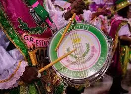 Ritimista durante carnaval, trajes coloridos, tambor verde e rosa.
