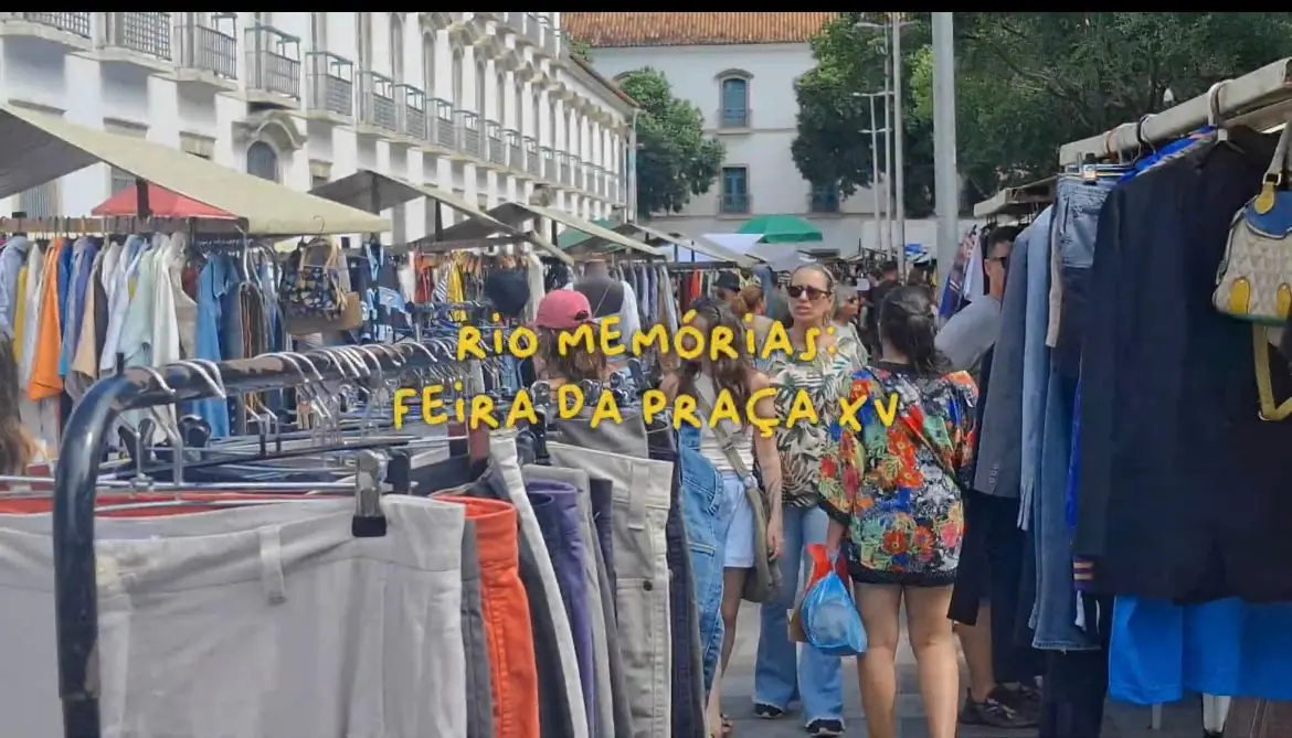 Feira de roupas em ambiente urbano, com variedade de calças e pessoas caminhando.