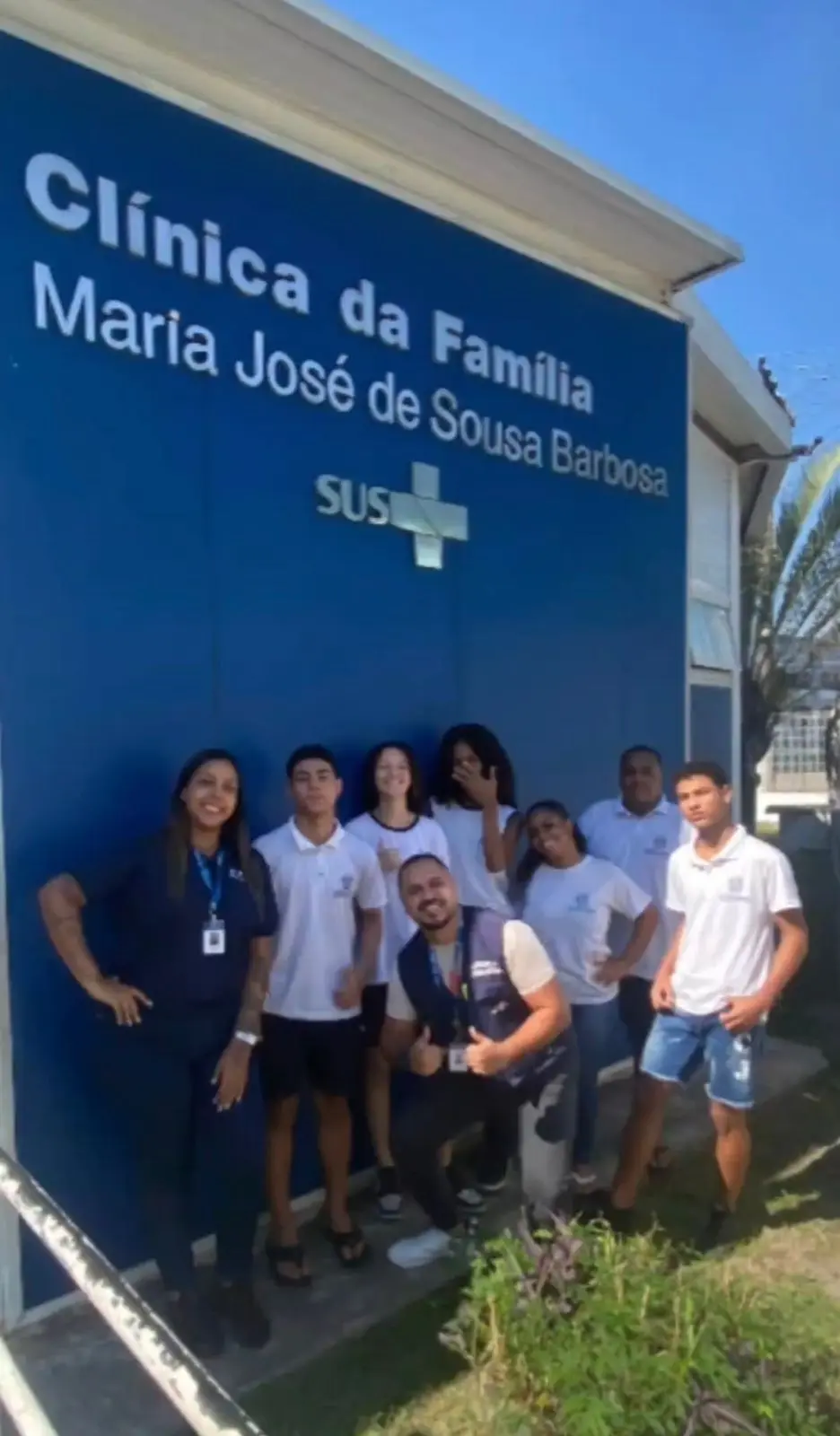 Grupo de pessoas sorrindo em frente à Clínica da Família Maria José de Sousa Barbosa.