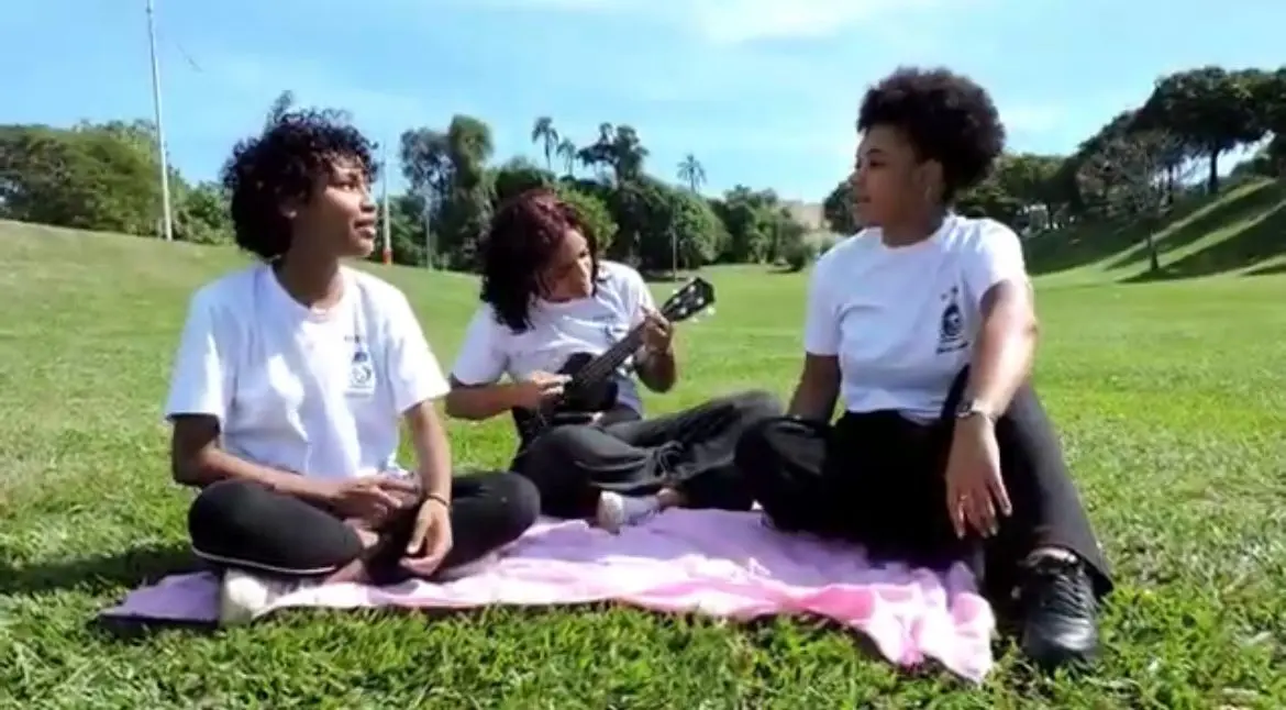 Três amigos se divertem ao ar livre em um gramado verde.
