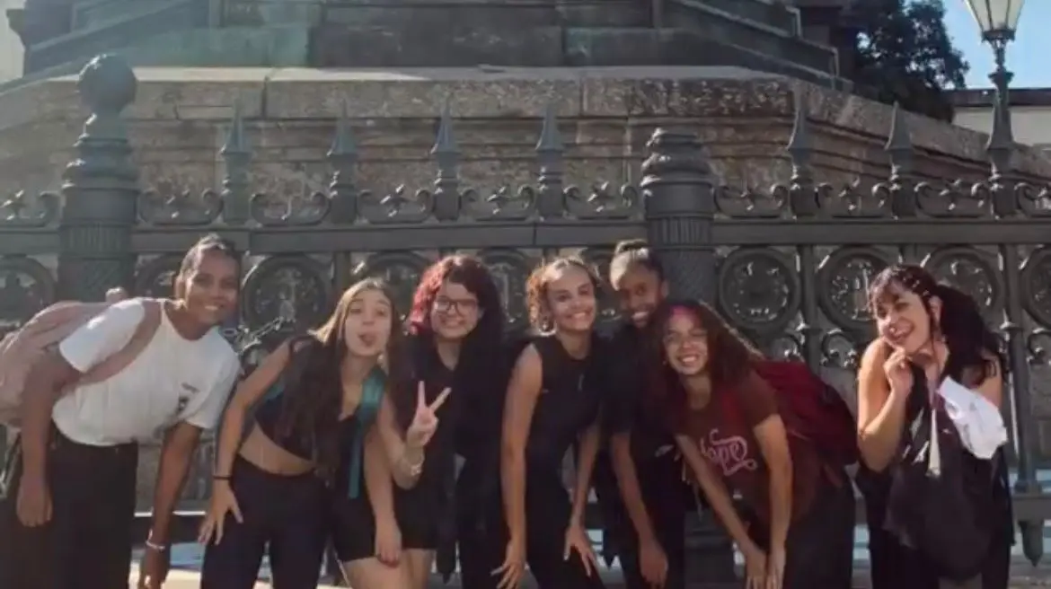 Pessoas sorridentes em frente a um monumento, dia ensolarado.
