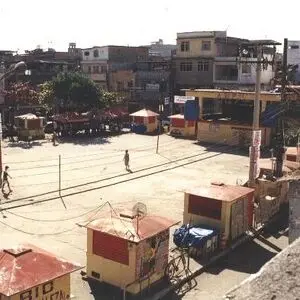 Praça urbana com barracas coloridas e pessoas caminhando.