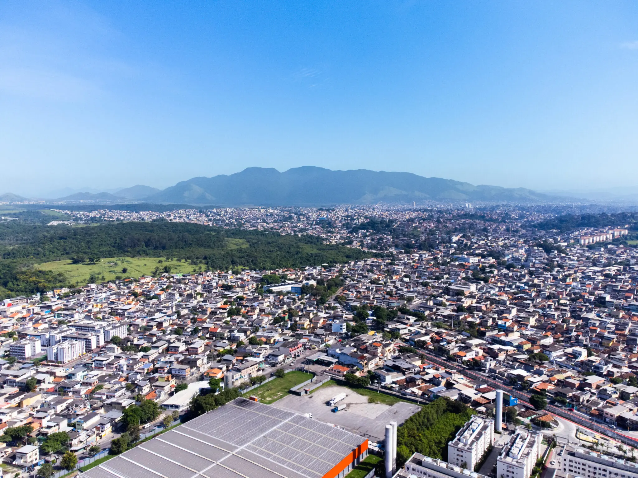 Cidade com áreas verdes, edifícios residenciais e montanhas distantes.