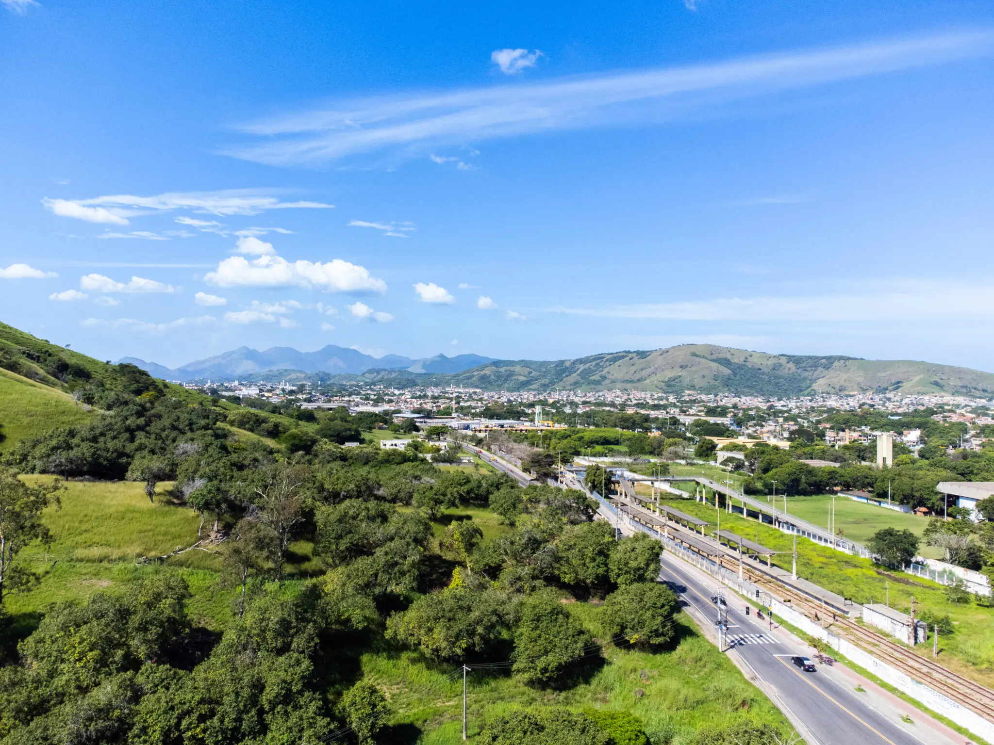 Paisagem com montanhas, estrada, carro e linha de trem.