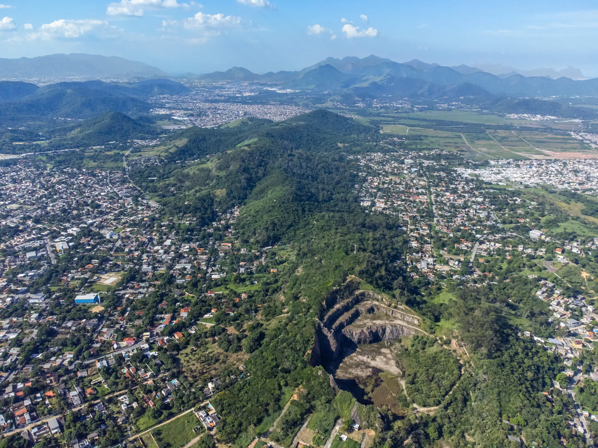 Área montanhosa com cidade, vegetação, formação rochosa e campos agrícolas.