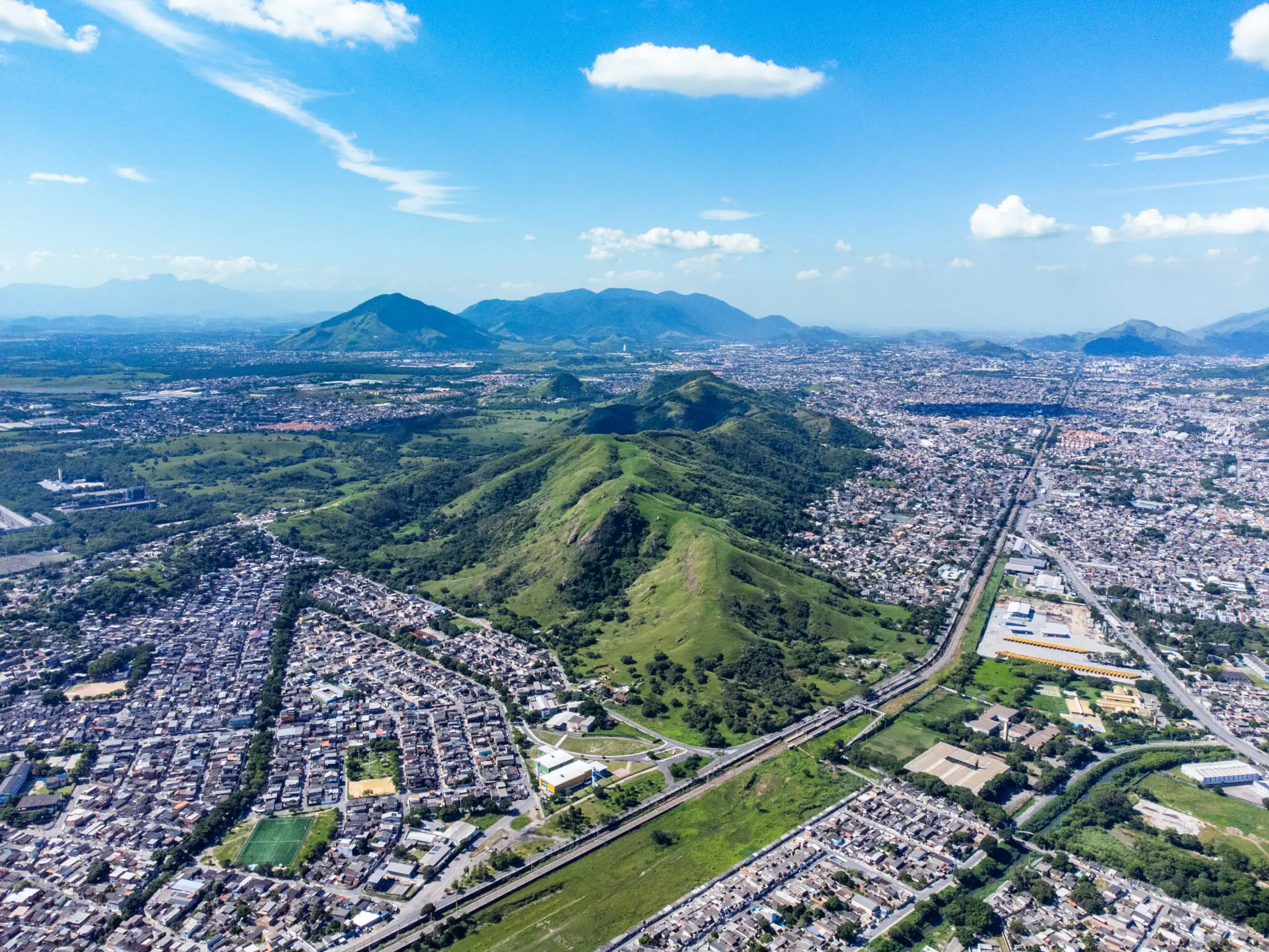 Área urbana rodeada por serras com edifícios residenciais e áreas verdes.