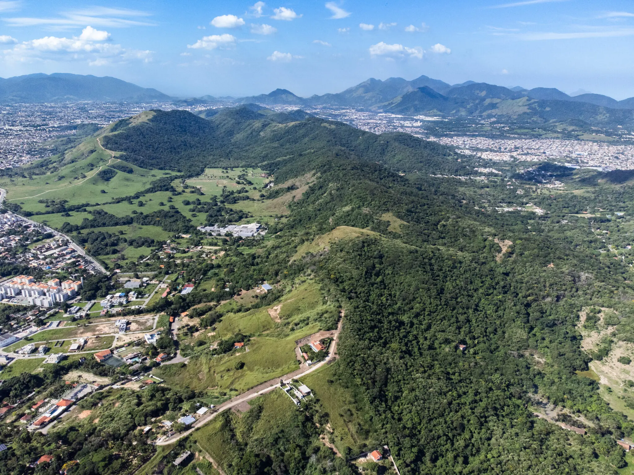 Área montanhosa com colinas verdes e cumes densamente cobertos de árvores.