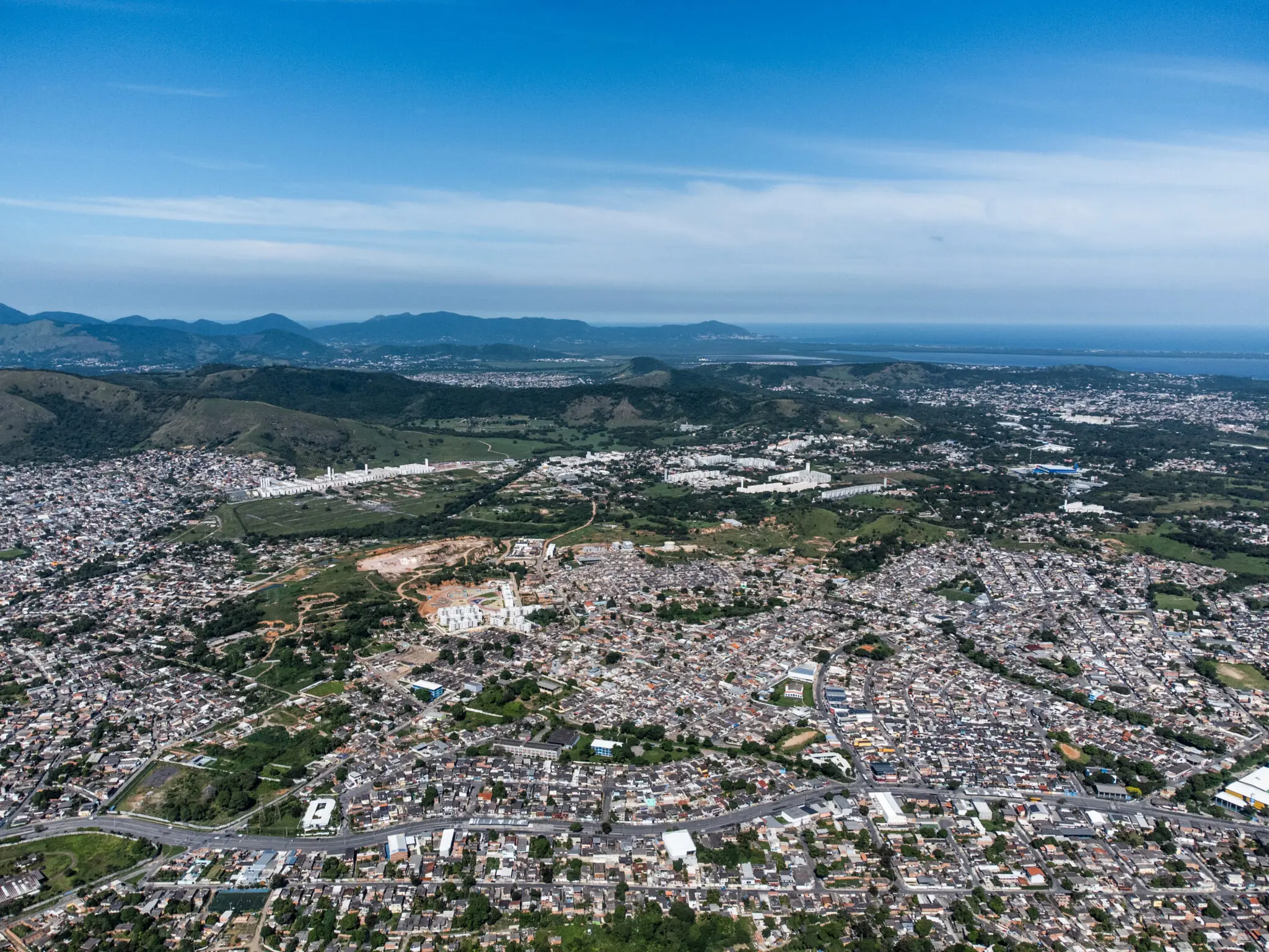Cidade rodeada por montanhas, com áreas verdes e edifícios residenciais e comerciais.