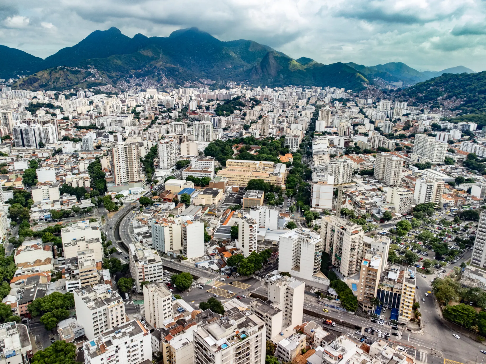 Cidade com edifícios, parque e montanhas verdes.