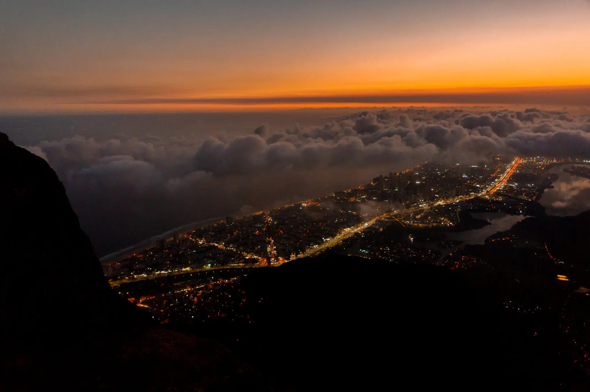 Paisagem urbana ao pôr-do-sol com iluminação cênica e nuvens baixas.
