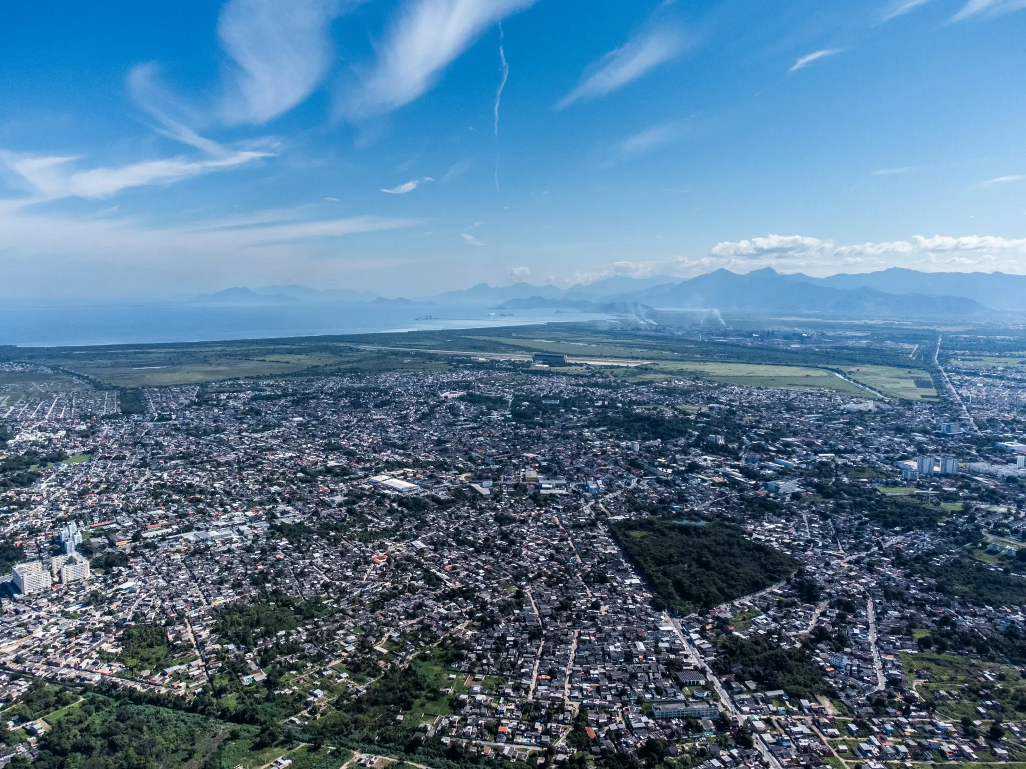 Cidade aérea com áreas verdes, construções e campos abertos.