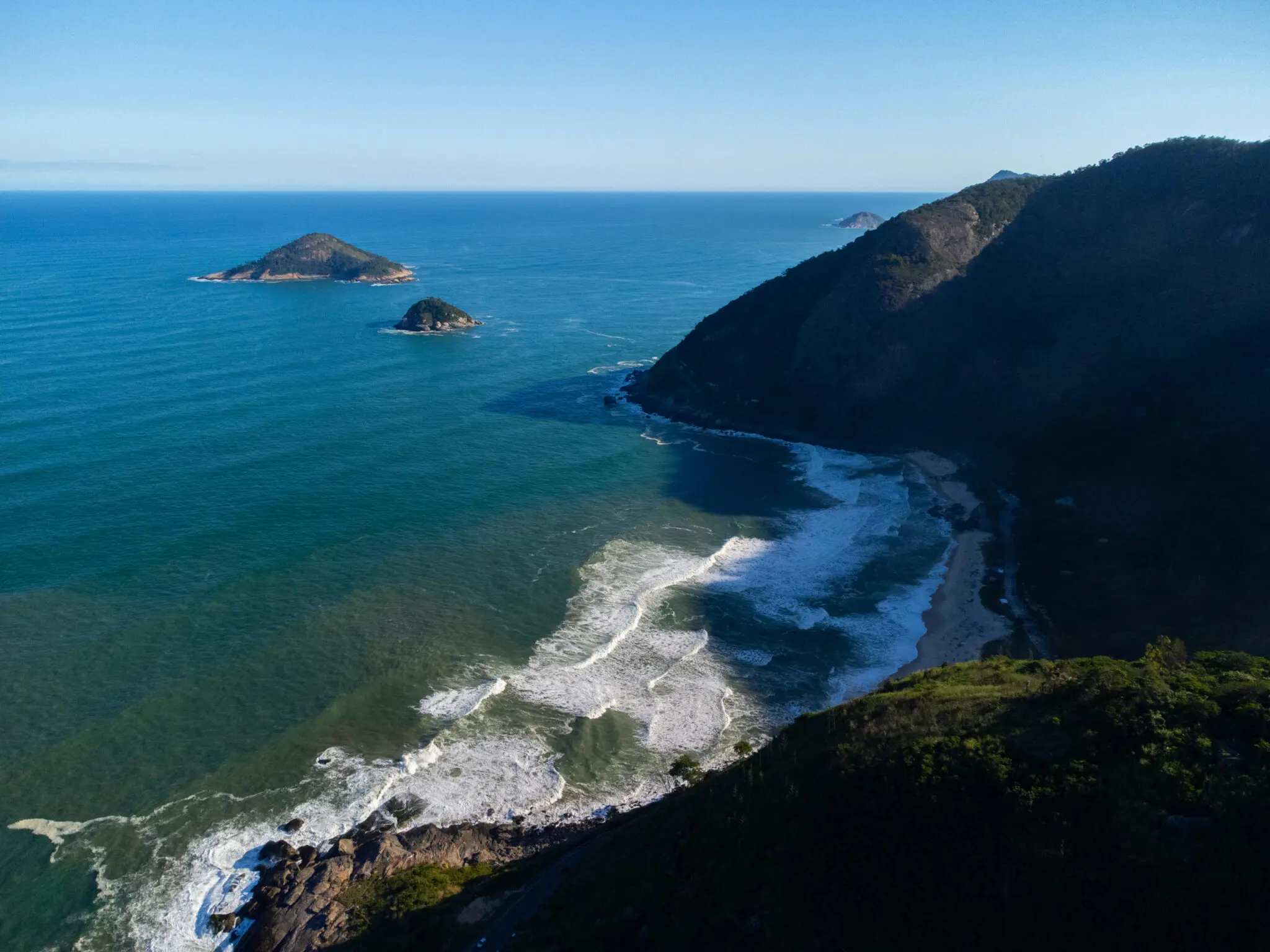Paisagem costeira com ilhas e montanha verde.