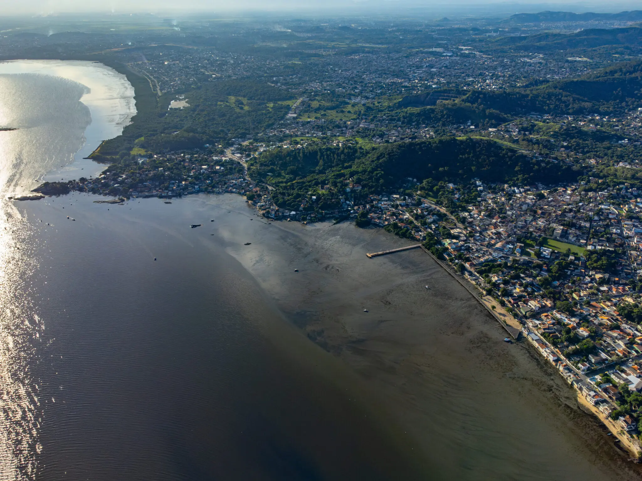 Área costeira com baía, casas e áreas verdes.