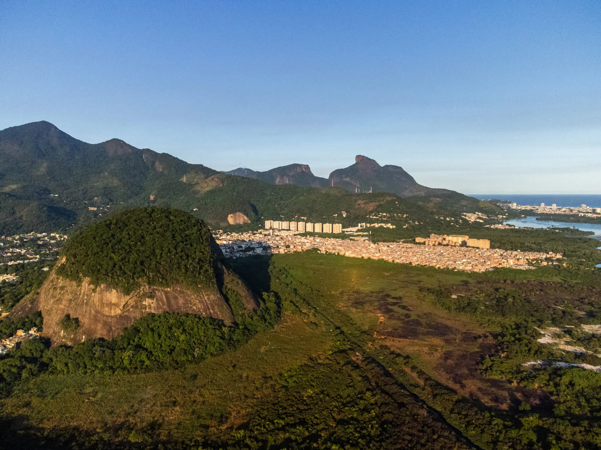 Paisagem montanhosa com cidade e vegetação verde.