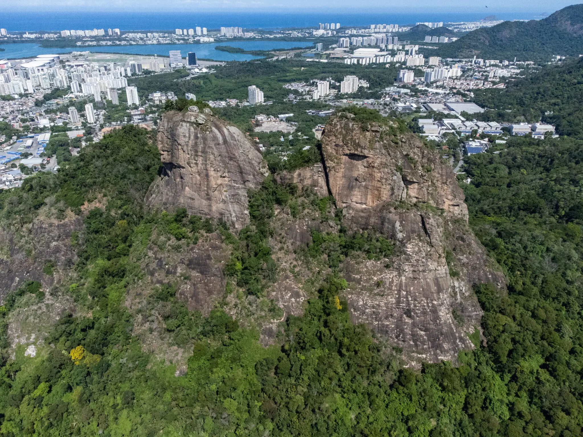 Área montanhosa com vegetação densa e cidade ao fundo.