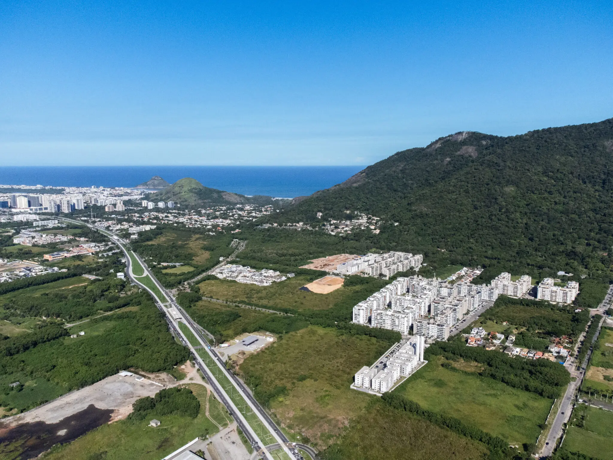 Área costeira com vegetação e edifícios residenciais.