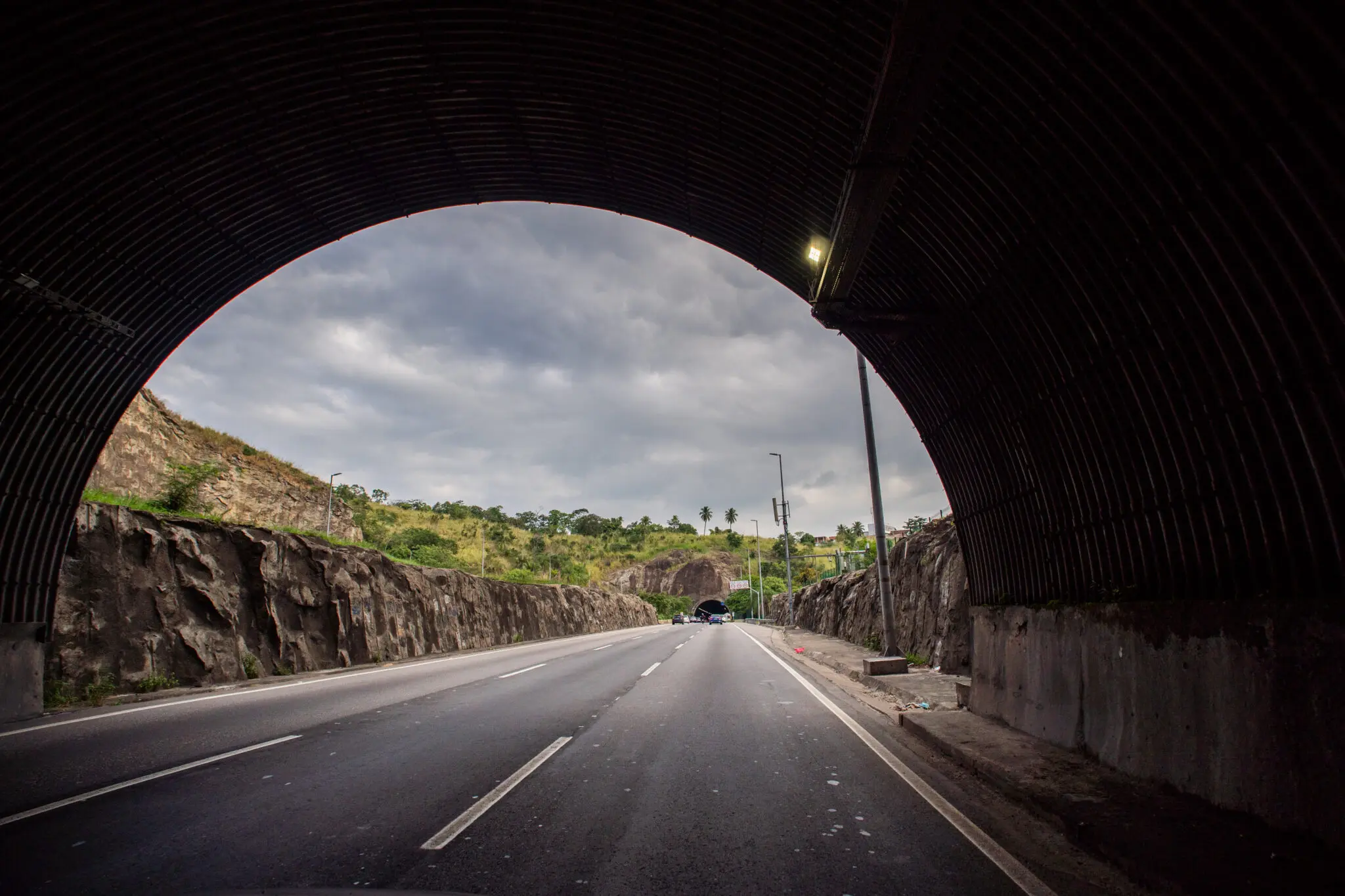 Túnel rodoviário com estrada e vegetação verde.